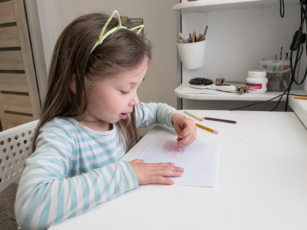 Little girl draws with colored pencils with her left hand