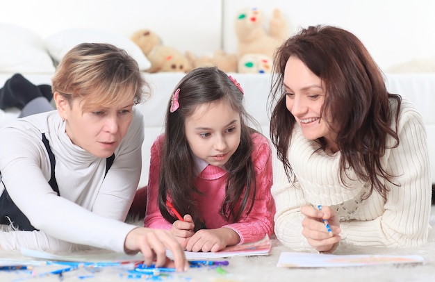 Little girl draws with her mother and grandmother.