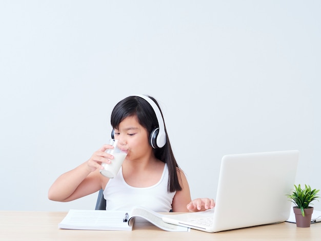 Little girl drinking milk while studying