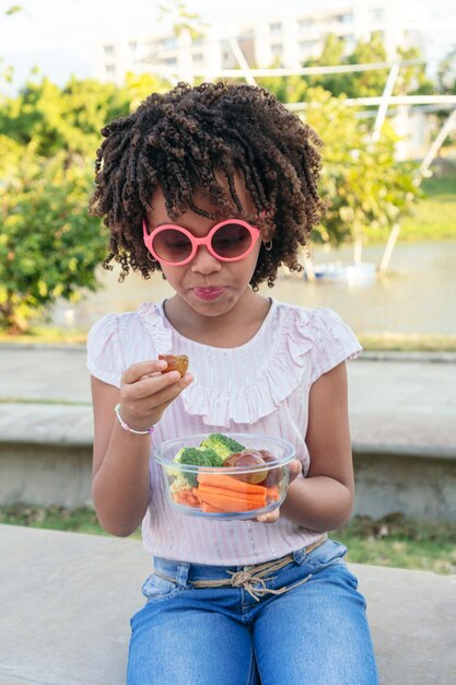 Little girl eating healthy food in a park Family lifestyle concept