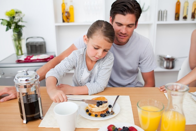 Little girl eating pancakes with her father