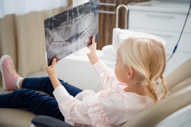 A little girl examines a panoramic X-ray of a patient s teeth