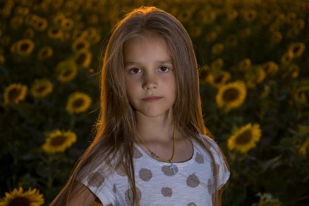 Little girl on the field with sunflowers blurred background