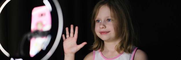 Little girl filming social media video using mobile phone and ring lamp