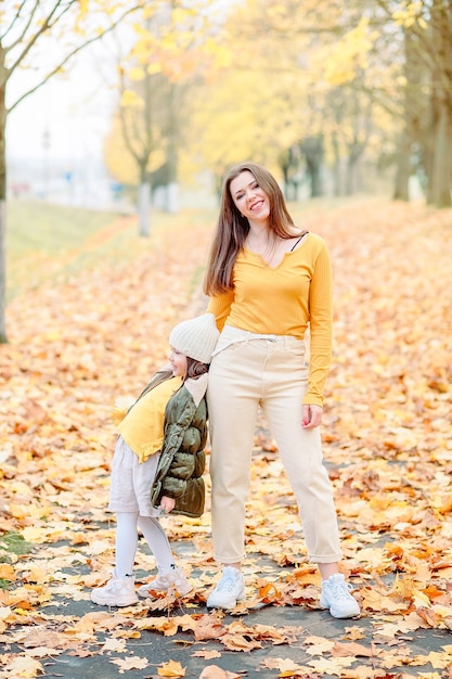 A little girl of five years old, opening her mouth with admiration and joy, plays with her mother in the autumn park. mom and daughter have fun outdoors in autumn