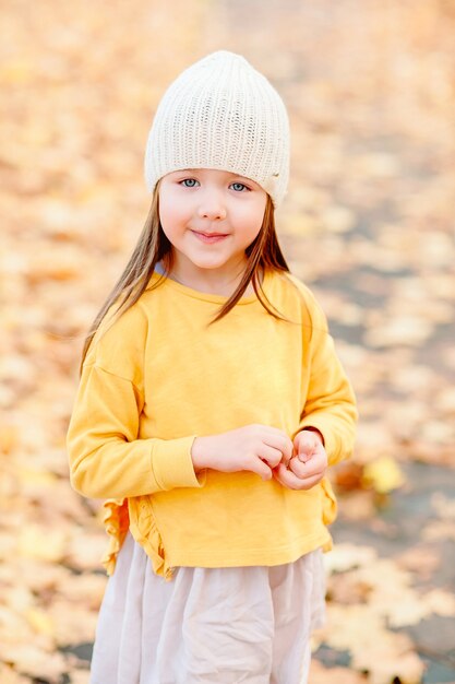 Little girl of five years old smiling cute at the camera in autumn clothes in October