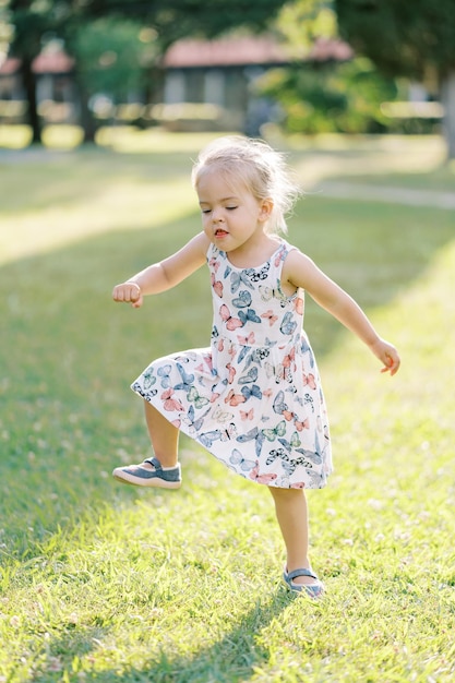 Little girl funny stamping her feet in a sunny meadow and waving her arms