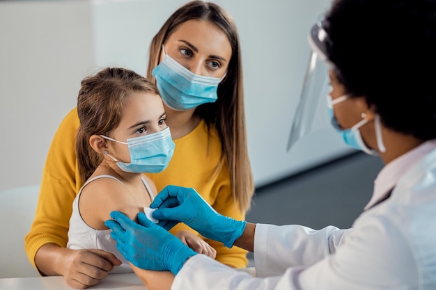 Little girl getting adhesive bandage on her arm after vaccination at medical clinic