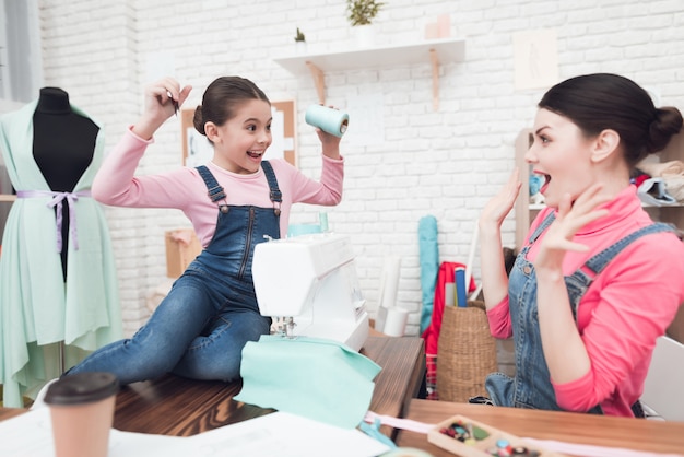 A little girl gives a woman threads.