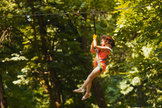 The little girl goes down the zipline in the park