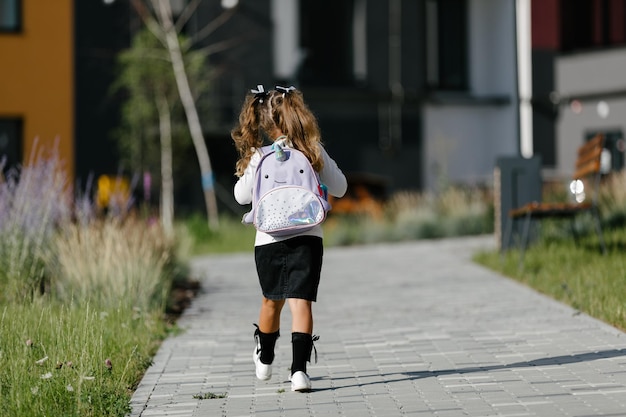 a little girl goes to school through the park along the path. distance education concept. schoolgirl