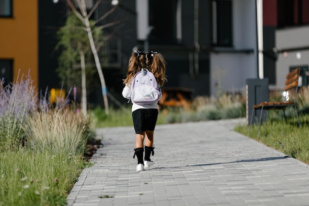 a little girl goes to school through the park along the path. distance education concept. schoolgirl