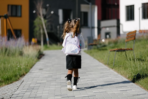 a little girl goes to school through the park along the path. distance education concept. schoolgirl