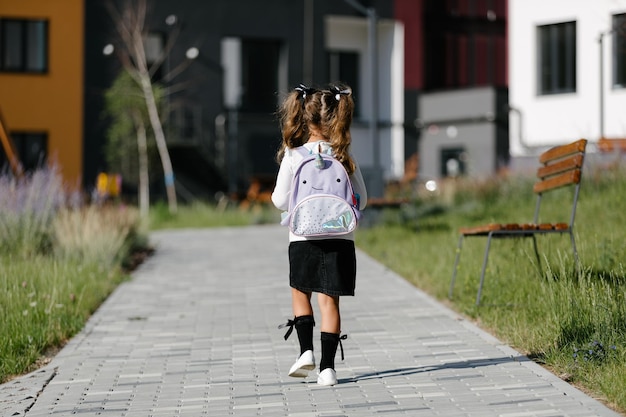 a little girl goes to school through the park along the path. distance education concept. schoolgirl