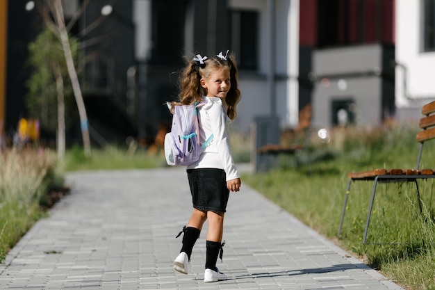 a little girl goes to school through the park along the path. distance education concept. schoolgirl