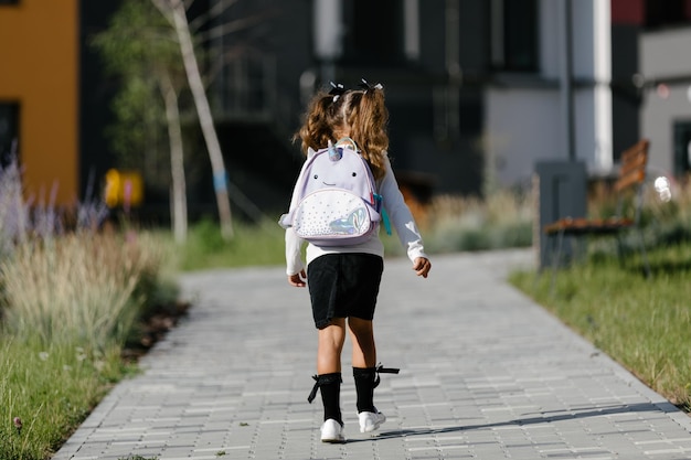 a little girl goes to school through the park along the path. distance education concept. schoolgirl