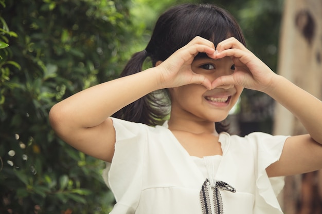 Little girl hands making a heart shape on white background