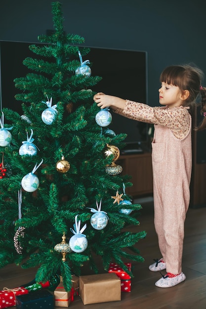 Little girl hanging ornaments on a Christmas tree