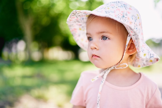 Photo little girl in a hat on a green meadow portrait