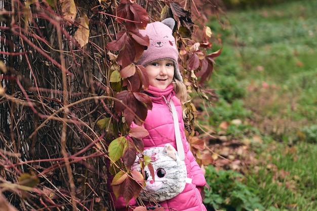 Little girl having fun in beautiful park with dry yellow and red leaves autumn family walk in forest