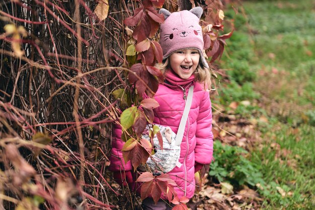 Little girl having fun in beautiful park with dry yellow and red leaves autumn family walk in forest