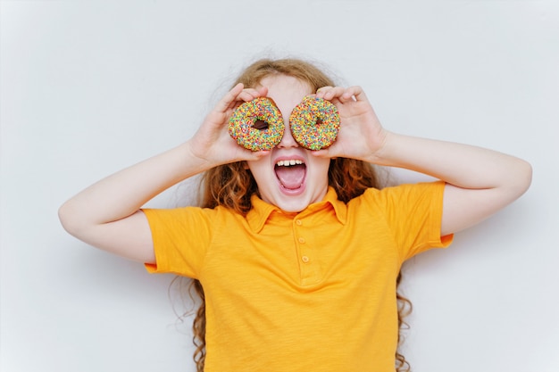 Photo little girl having fun with donuts eyes. 