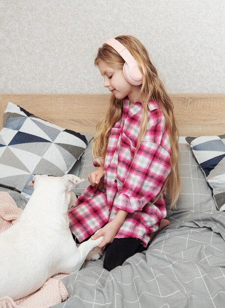 Little girl in headphones playing with her dog