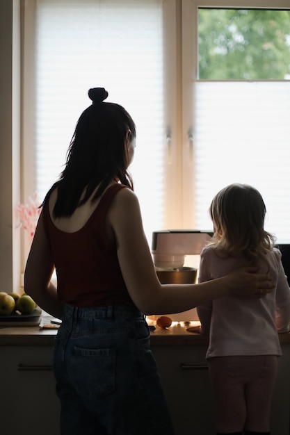 Little girl helping her mother cooking in the kitchen