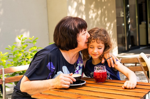 Little girl and her grandmother drink coffee and cocktail