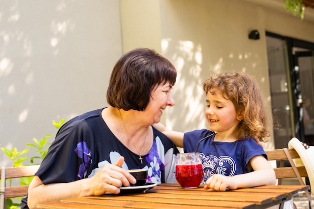 Little girl and her grandmother drink coffee and cocktail