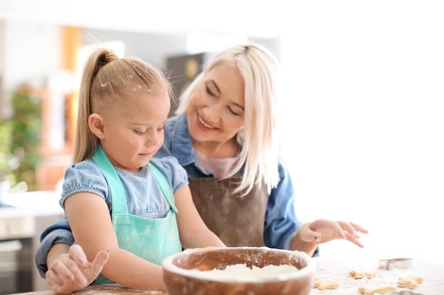 Little girl and her grandmother with flour and cookie dough at table in kitchen