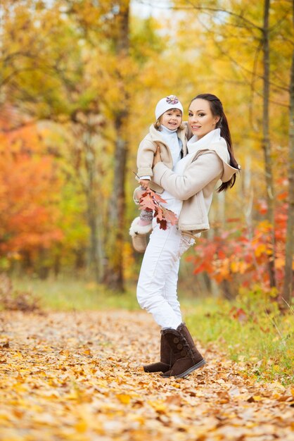 Little girl and her mother playing in the autumn park.