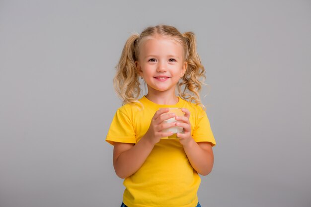 little girl holding a glass of milk on a light background, space for text