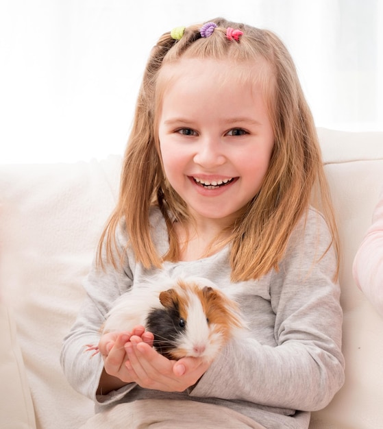 Photo little girl holding guinea pig on hands