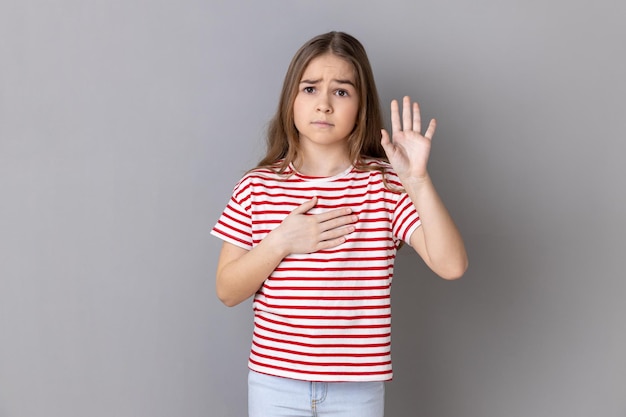 Little girl holding hand on heart swearing to speak truth honor and conscience