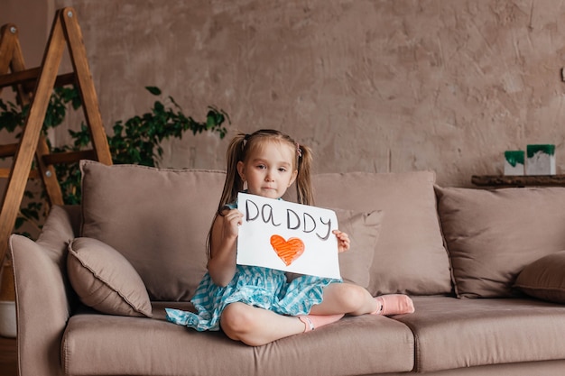 Little girl holding a homemade heartshaped drawing as a gift for Fathers Day