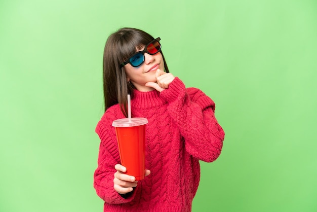 Little girl holding soda over isolated chroma key background and looking up