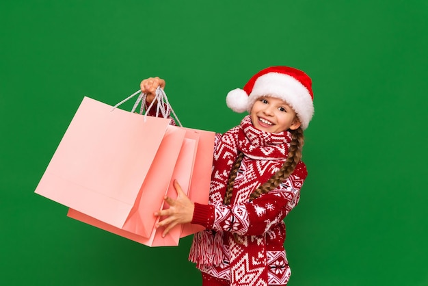 A little girl holds bags with gifts for Christmas Christmas discounts in stores for the holiday Children in a New Year's sweater with bags from the store