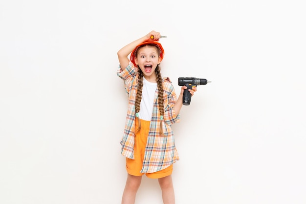 A little girl holds a drill on a white isolated background The child points up at your advertisement The concept of renovation in the children's room