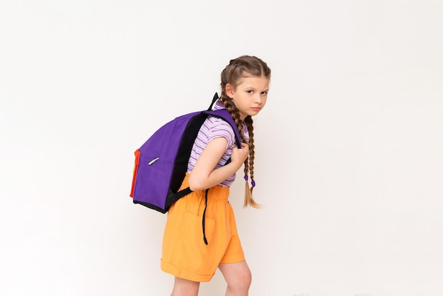 A little girl holds a heavy school satchel behind her back on a white isolated background What is the weight of the backpack the child should have