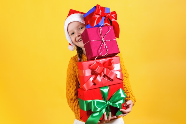 Little girl holds a lot of boxes with Christmas gifts.