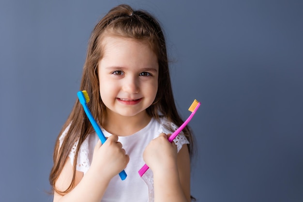 A little girl holds a toothbrush in her hands.