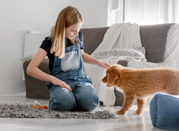 Little girl at home on the floor with nova scotia retriever puppy a toller