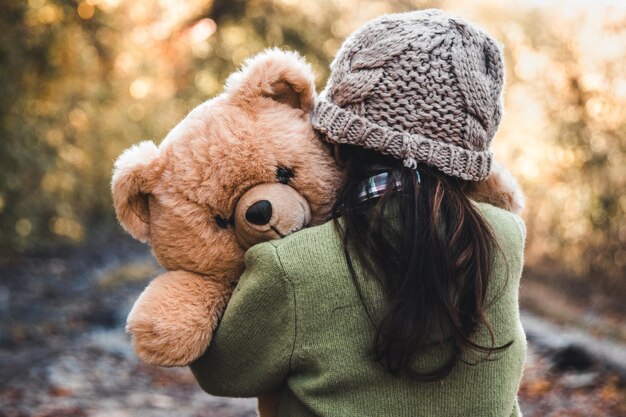 Photo little girl hugs her bear on a background of nature autumn durba