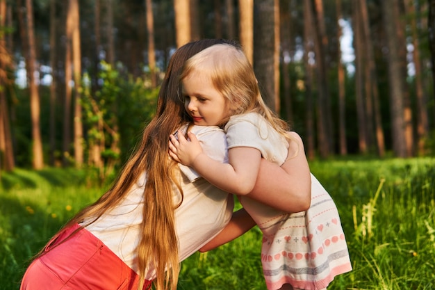 Little girl hugs her mother tightly while walking in nature