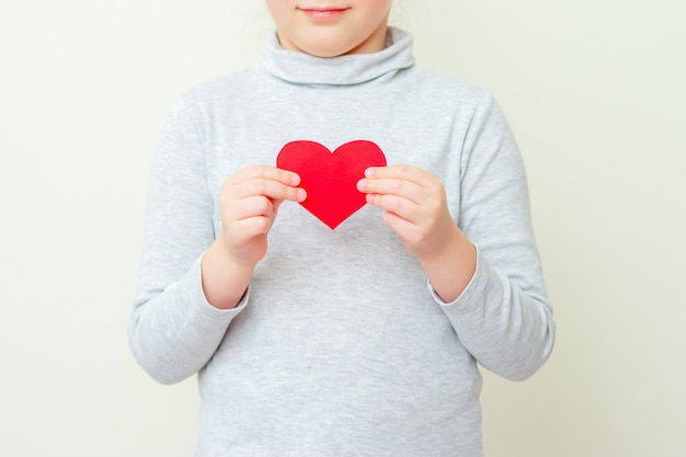 Little girl is holding red little heart.