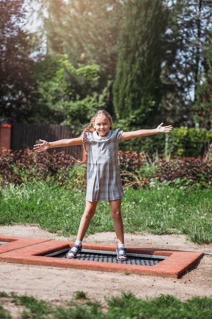 Little girl is jumping on trampoline in a park Happy laughing kid outdoors in the yard on summer vacation Jump high