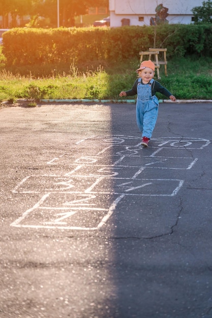 A little girl is playing hopscotch on the playground