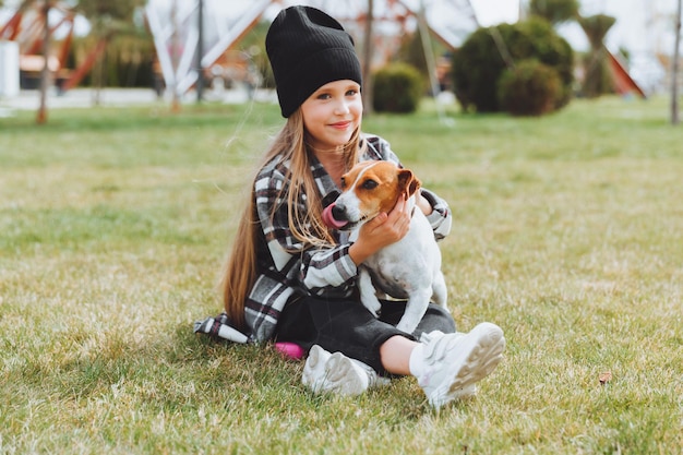 A little girl is playing with her dog on the grass in the park jack Russell terrier a child gives a toy to his dog