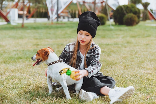 A little girl is playing with her dog on the grass in the park jack Russell terrier a child gives a toy to his dog